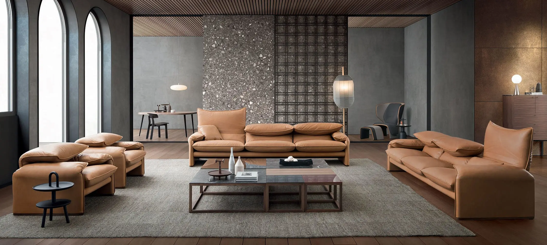 Living room with Cassina tan leather sofas and armchairs around a low wood and glass coffee table, arched windows behind