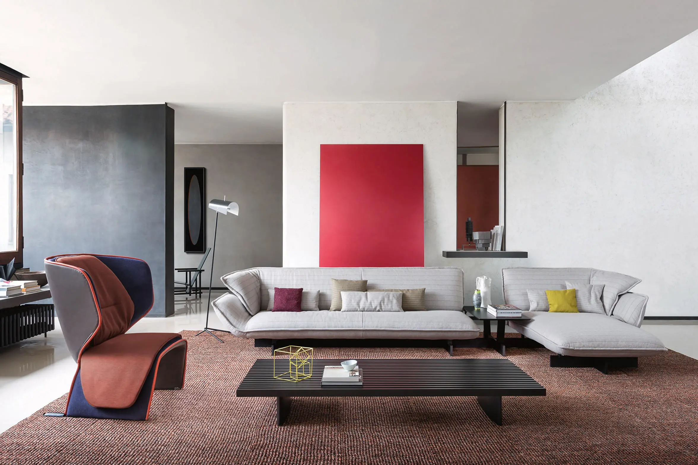 Cassina living room with a white sectional sofa, low dark coffee table, red armchair and red artwork