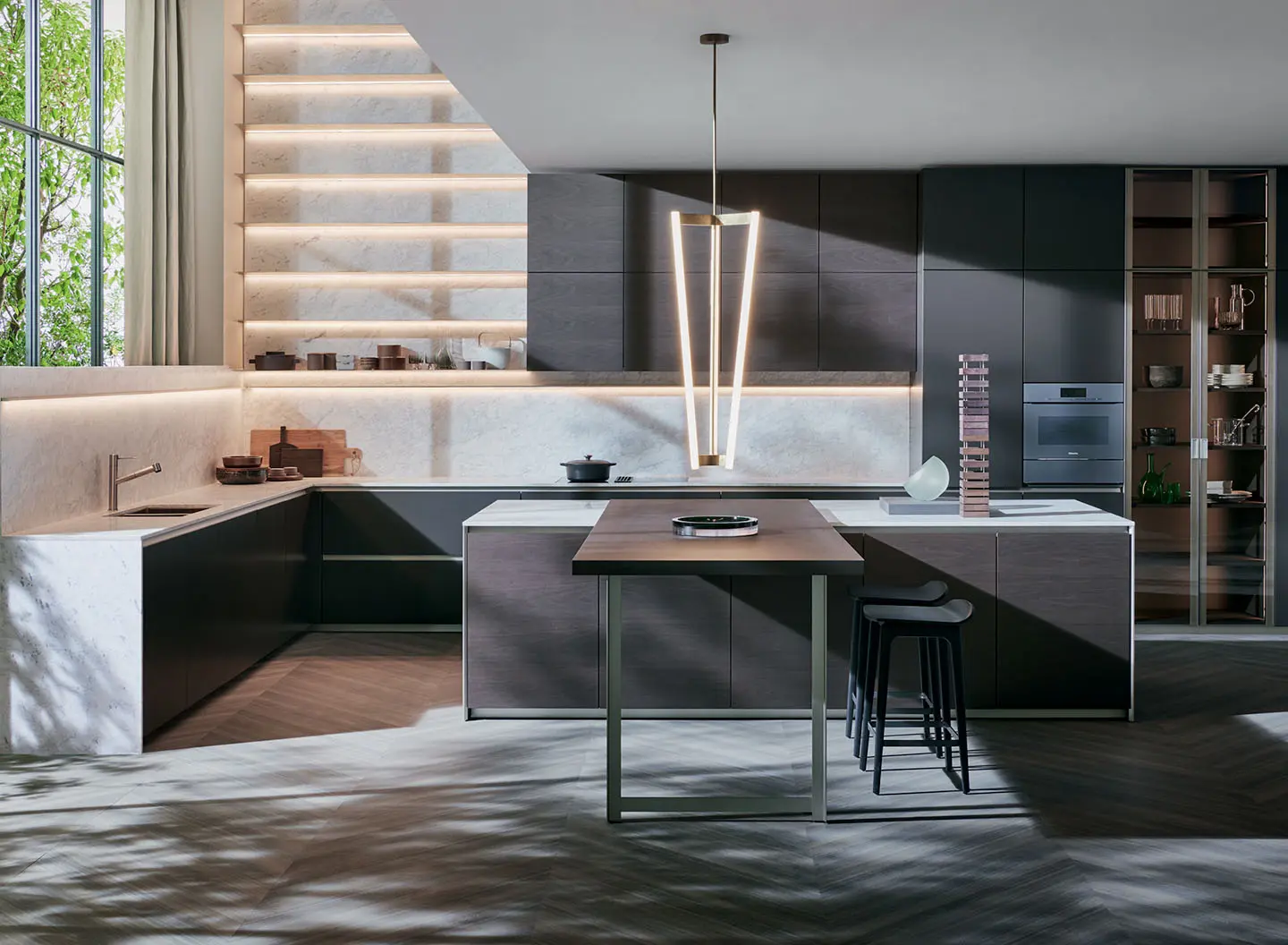 Dada kitchen with dark cabinets, an island with bar stools and a pendant light