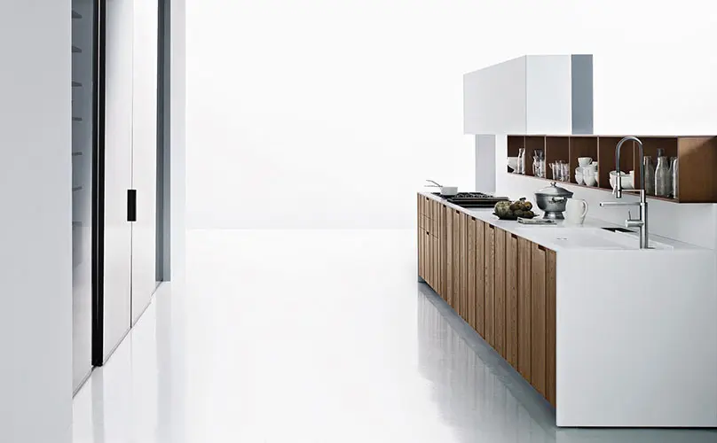 Minimalist white kitchen island with wood cabinet fronts in an all-white room