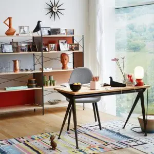 Home office with black shelving, orange accents, starburst clock and striped rug