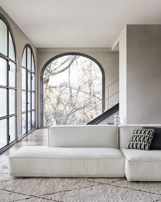 Arched glass doors opening onto a beige sectional sofa with a patterned bolster cushion