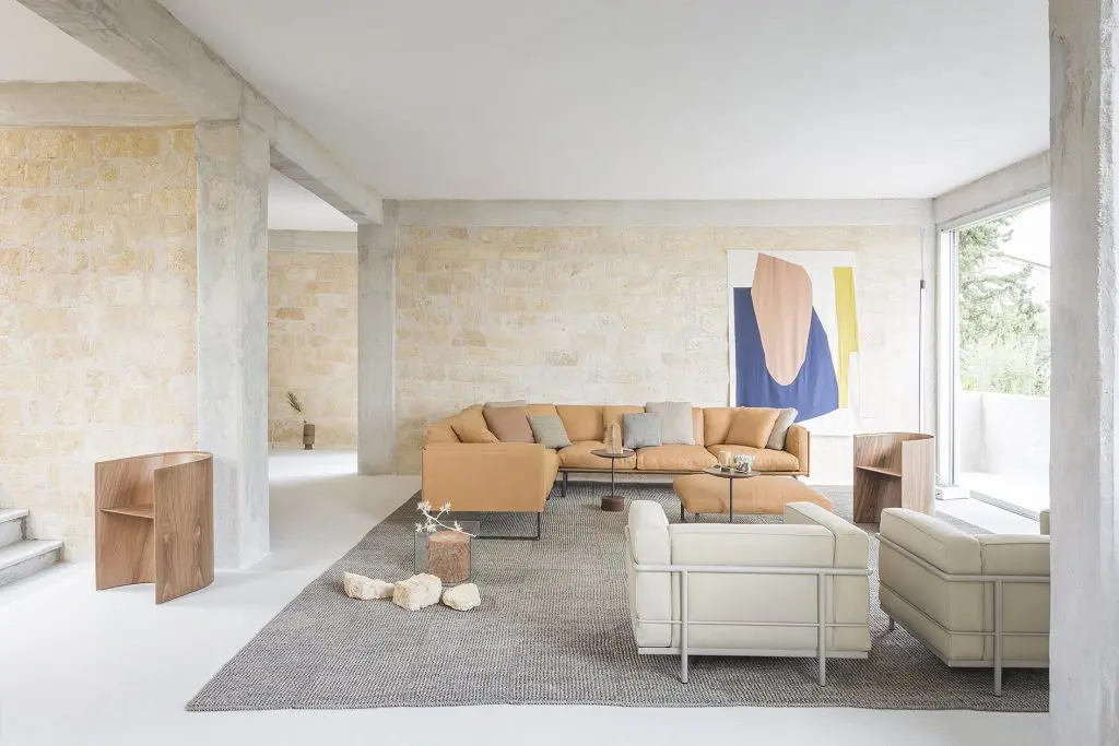 Sunlit living room with a tan leather sectional sofa and abstract framed artwork
