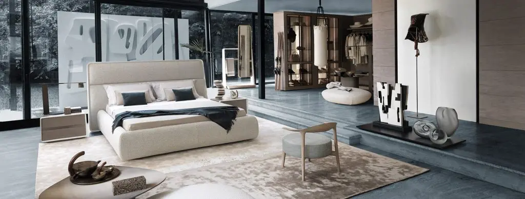 Bedroom with cream upholstered bed, walk-in closet and dressing area in the background
