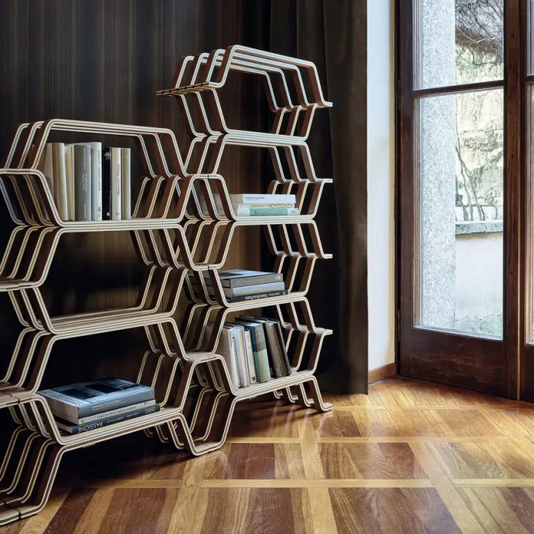Modular wood shelving unit with geometric zigzag frame holding books by a glass door