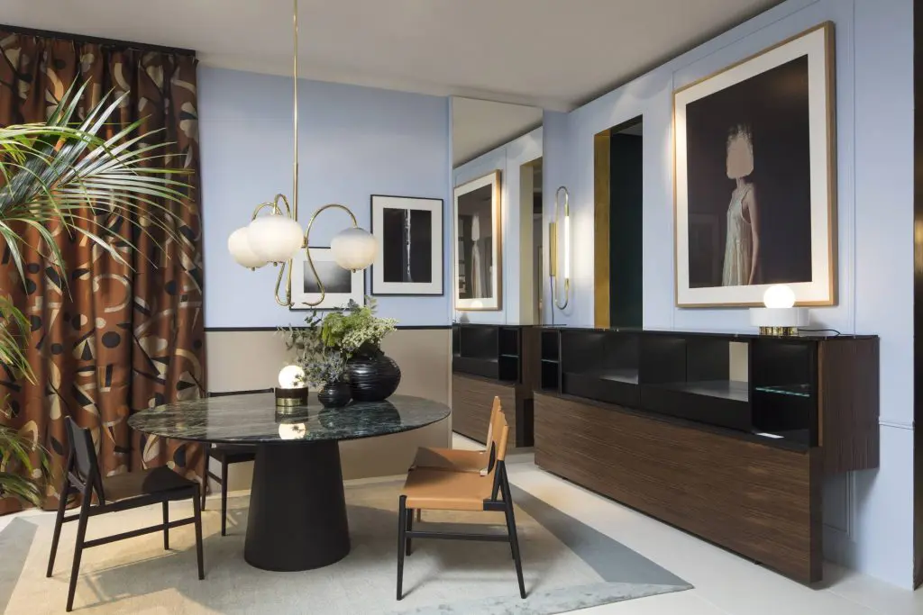 Dining nook with round black table, brass chandelier and framed portrait photography