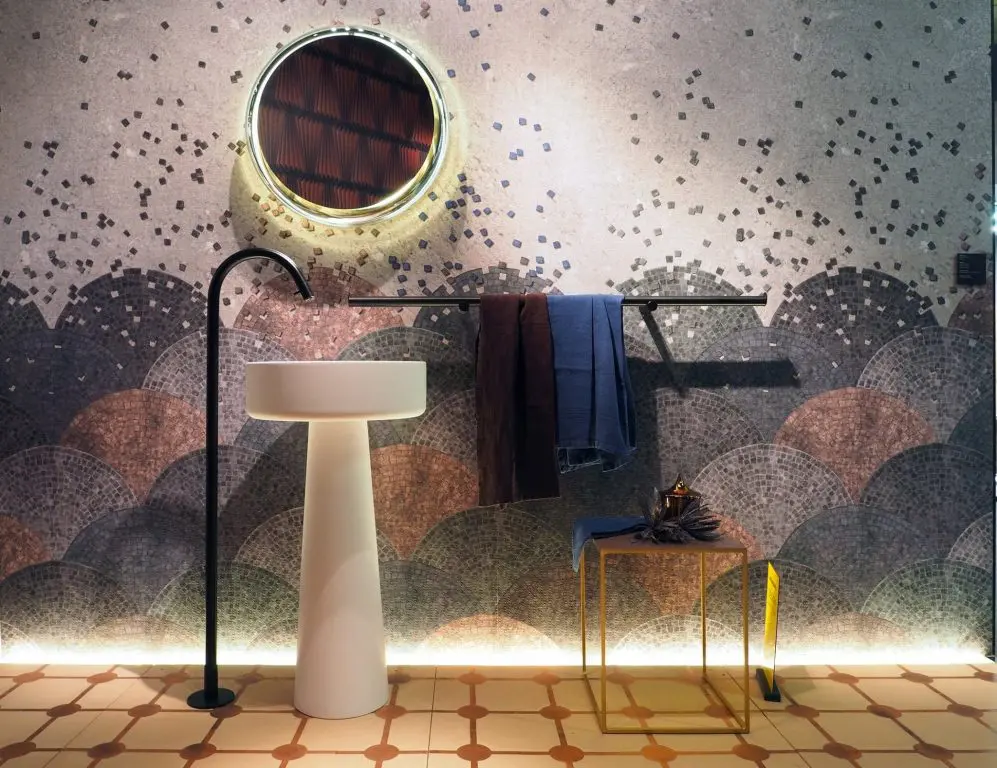 Agape bathroom with fish-scale mosaic tiles, a round porthole mirror and a white pedestal basin