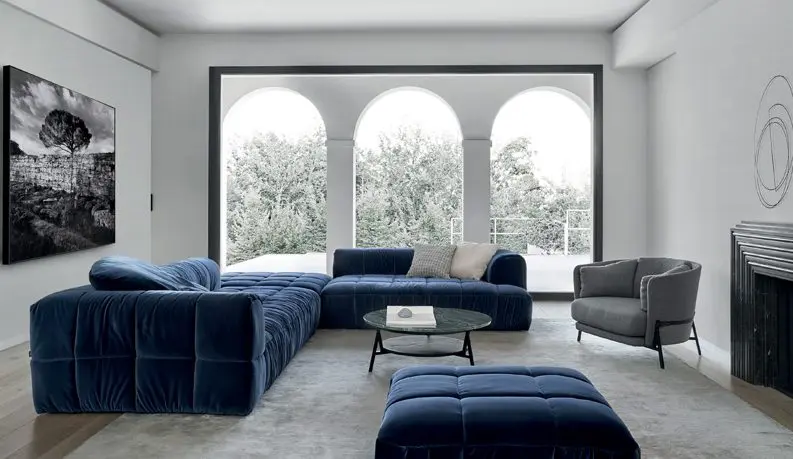 Living room with a navy blue velvet modular sofa, black metal accent chair and a black-and-white framed photograph