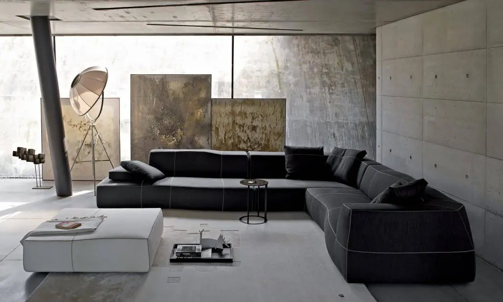B&B Italia living room with a charcoal grey modular sofa in an industrial concrete space with large paintings