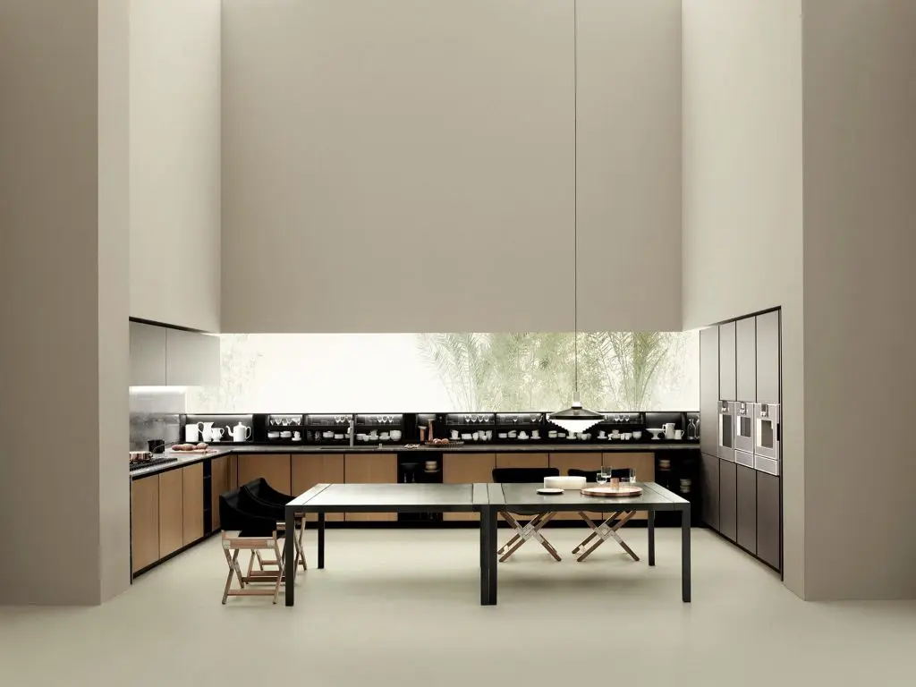 Boffi kitchen with tall cream cabinetry, a black dining table and a glass backsplash overlooking greenery