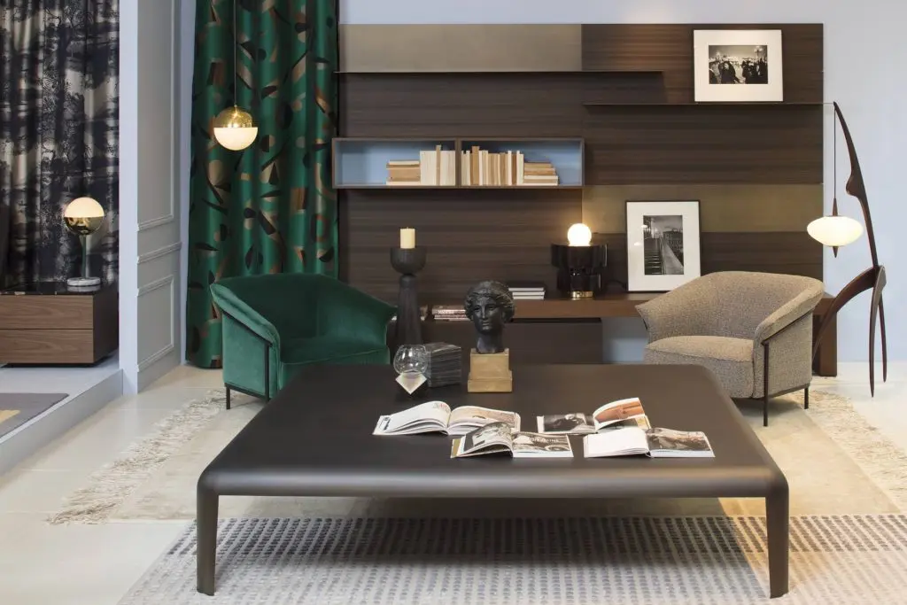 Contemporary living room with a dark wood wall unit, green velvet armchair, patterned curtains and a black coffee table
