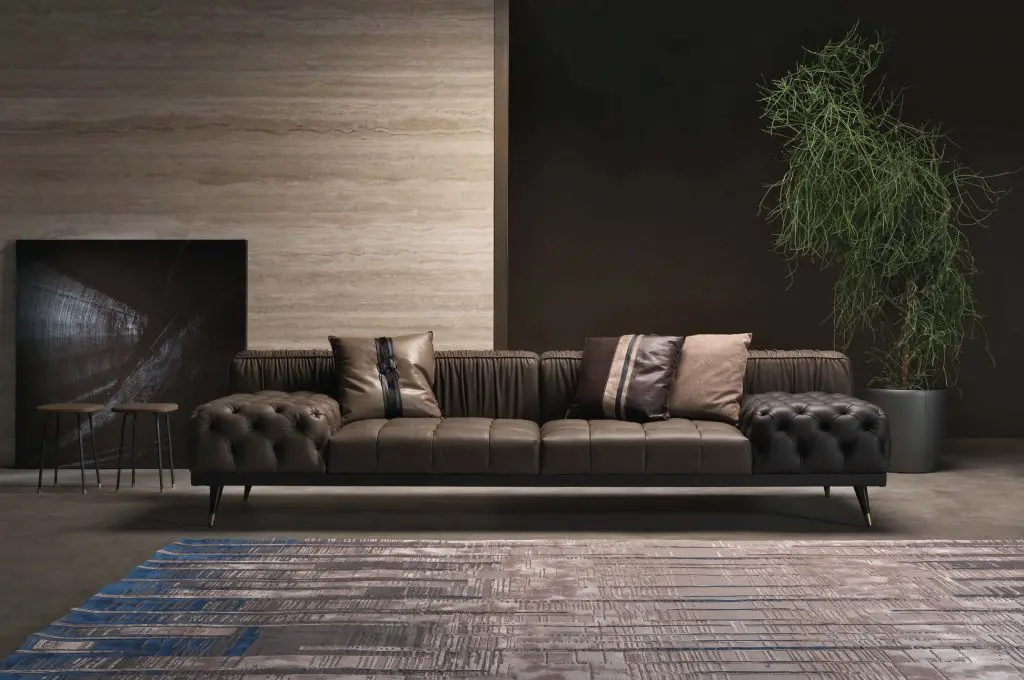 Gianfranco Ferré Home living room with a dark brown tufted leather sofa against a travertine wall
