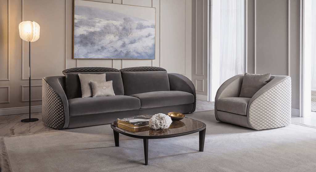 Bentley Home living room with a grey velvet sofa, matching quilted armchair and a dark wood oval coffee table