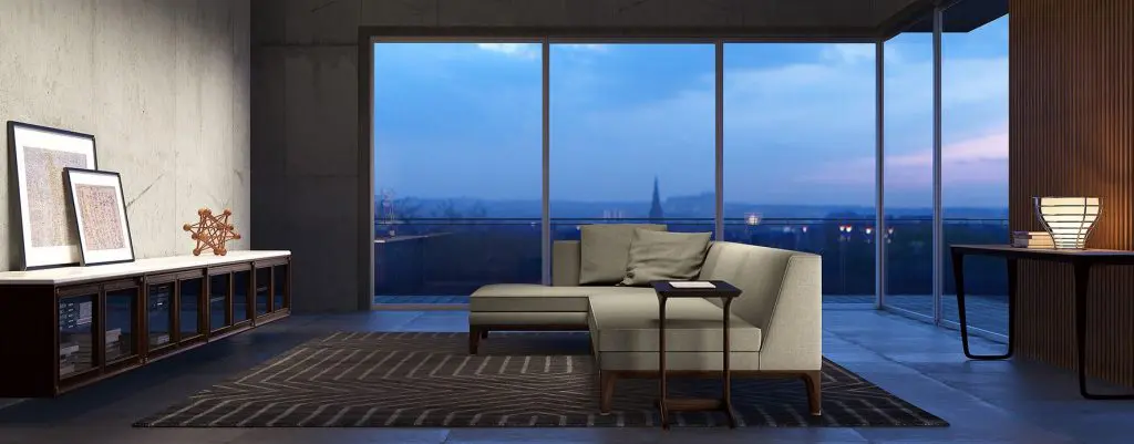 Contemporary living room with a grey chaise sofa, dark concrete wall and floor-to-ceiling windows over a city skyline at dusk