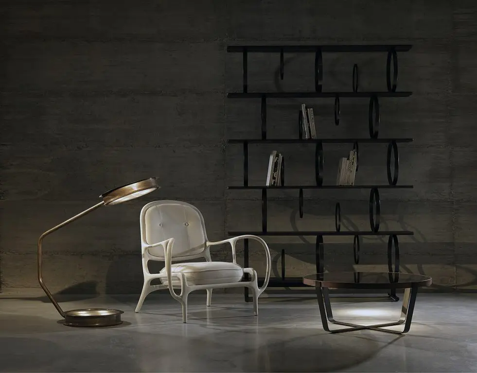 White bentwood armchair, black ring-patterned bookshelf and a round glass coffee table against a dark wall