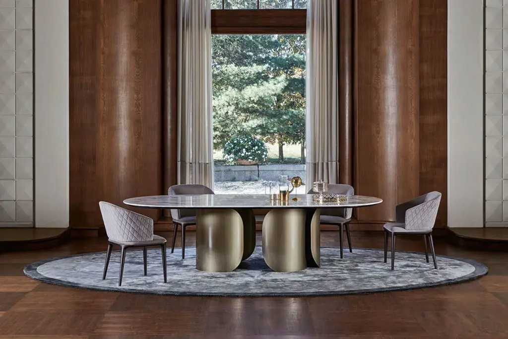 Opera Contemporary Oscar table: an oval marble top on sculptural brass pedestal legs, with grey dining chairs