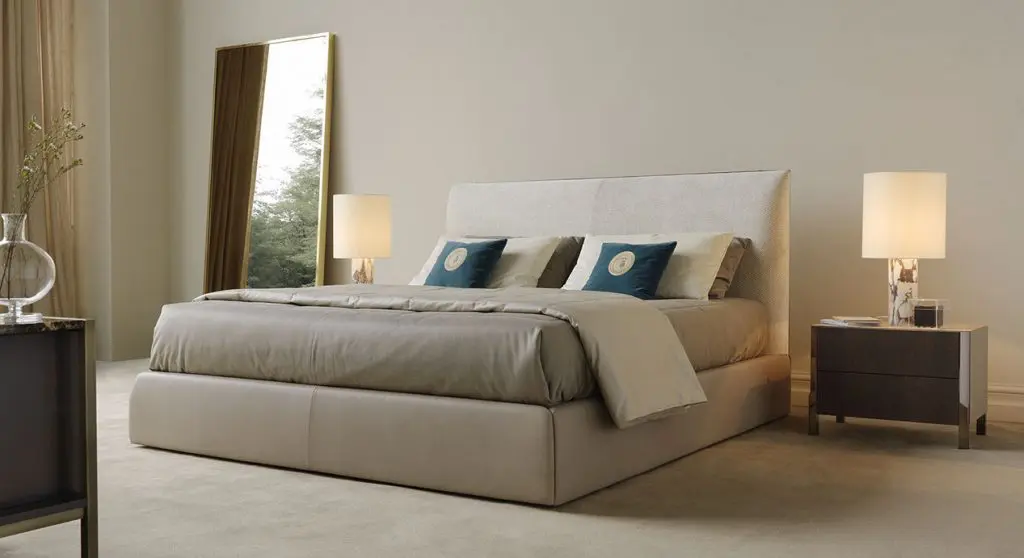 Trussardi Casa bedroom with an upholstered bed, teal accent cushions and a tall gold-framed mirror