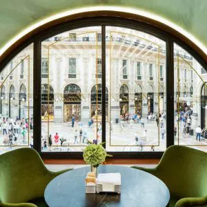 Arched window overlooking a Milan piazza with green armchairs