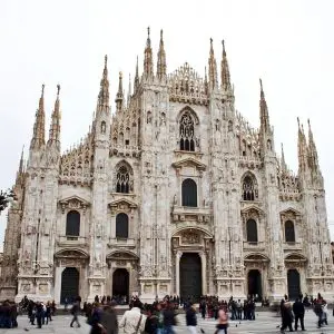 Milan's white Gothic cathedral facade with crowds in the square in front