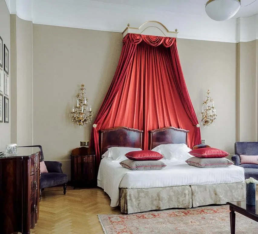 Bed with a red canopy drape and wall sconces