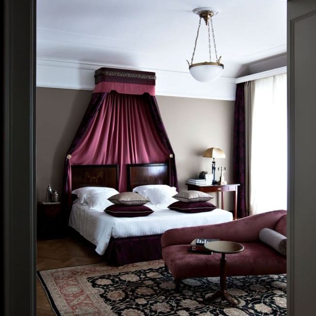 Suite with a burgundy canopy bed and matching chaise lounge