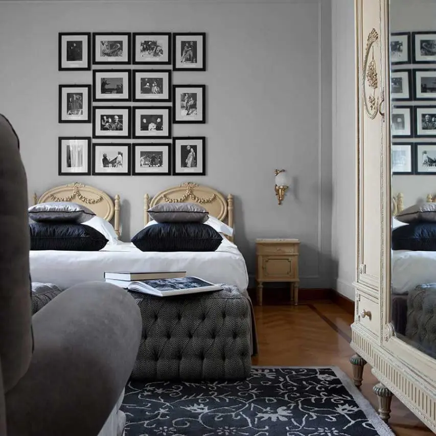 Bedroom with a gallery wall of framed photos and a tufted ottoman