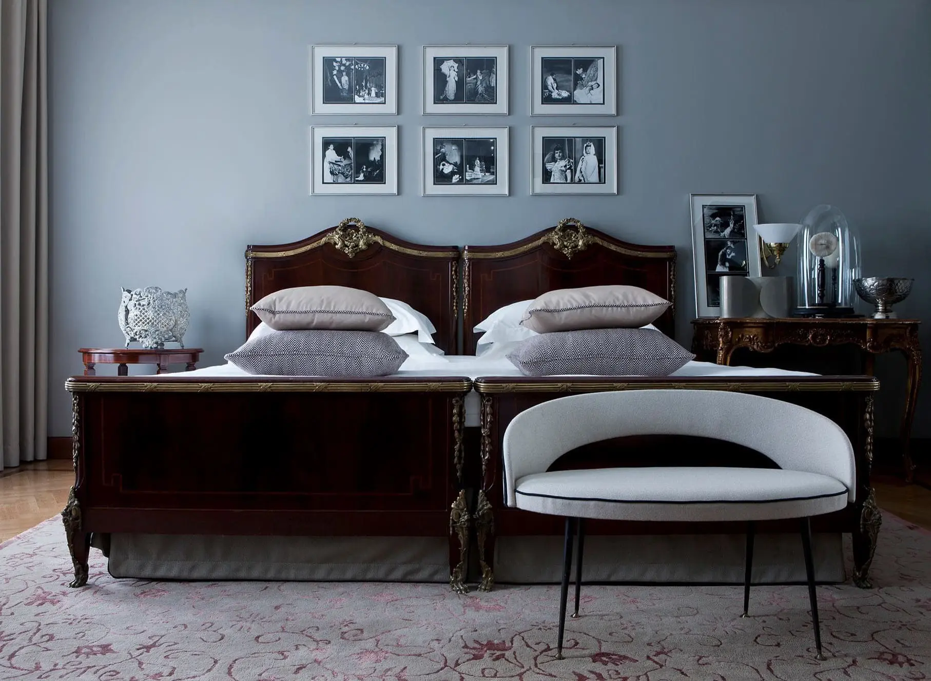 Hotel bedroom with dark wood twin beds joined together, framed photos and a curved bench