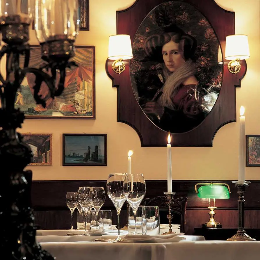 Restaurant table setting with candles beneath a portrait painting