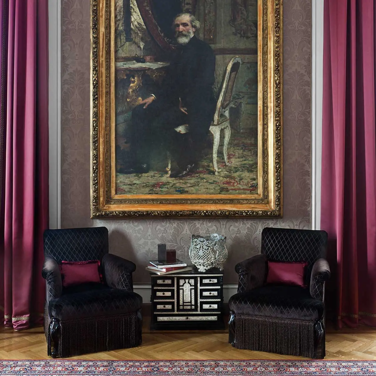 Pair of black velvet armchairs beneath a framed portrait