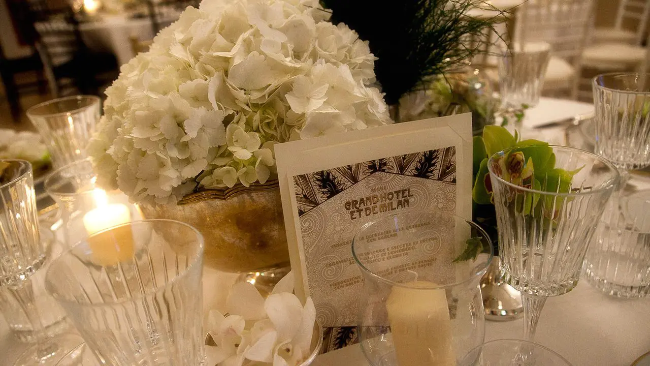 Table setting with a white hydrangea centerpiece, candles and a printed hotel menu card