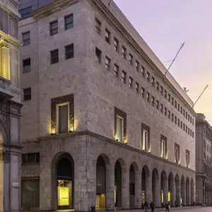 Historic stone building facade at dusk with arched ground-floor arcade