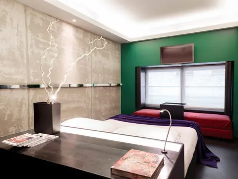Room with a green accent wall, branch sculpture and red daybed