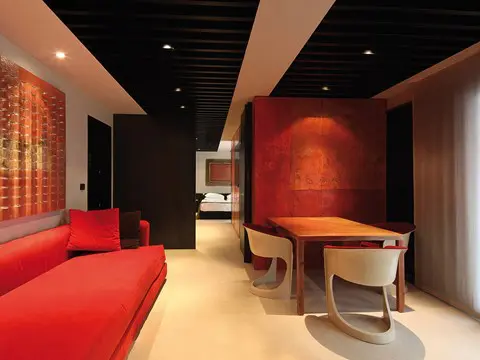 Living area with a red sofa and curved wooden dining chairs