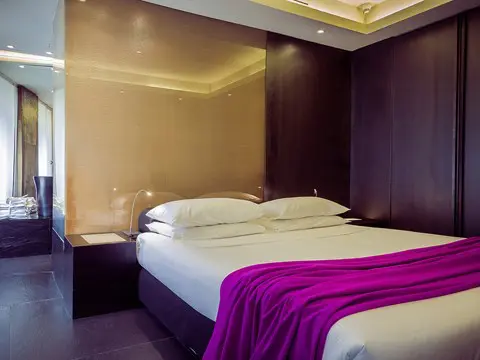 Bedroom with dark wood paneling and a purple throw blanket
