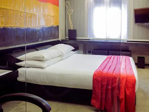 Bedroom with abstract wall art and a red throw on the bed