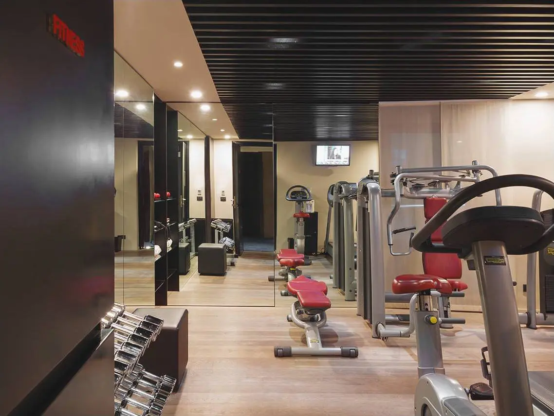 Hotel gym with red-accented machines, free weights and mirrored walls