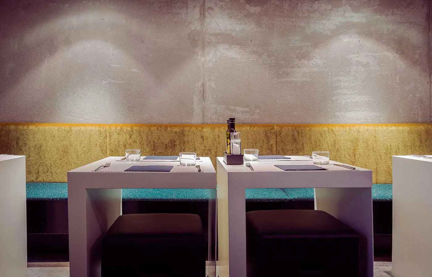 Minimalist restaurant tables set against a concrete wall