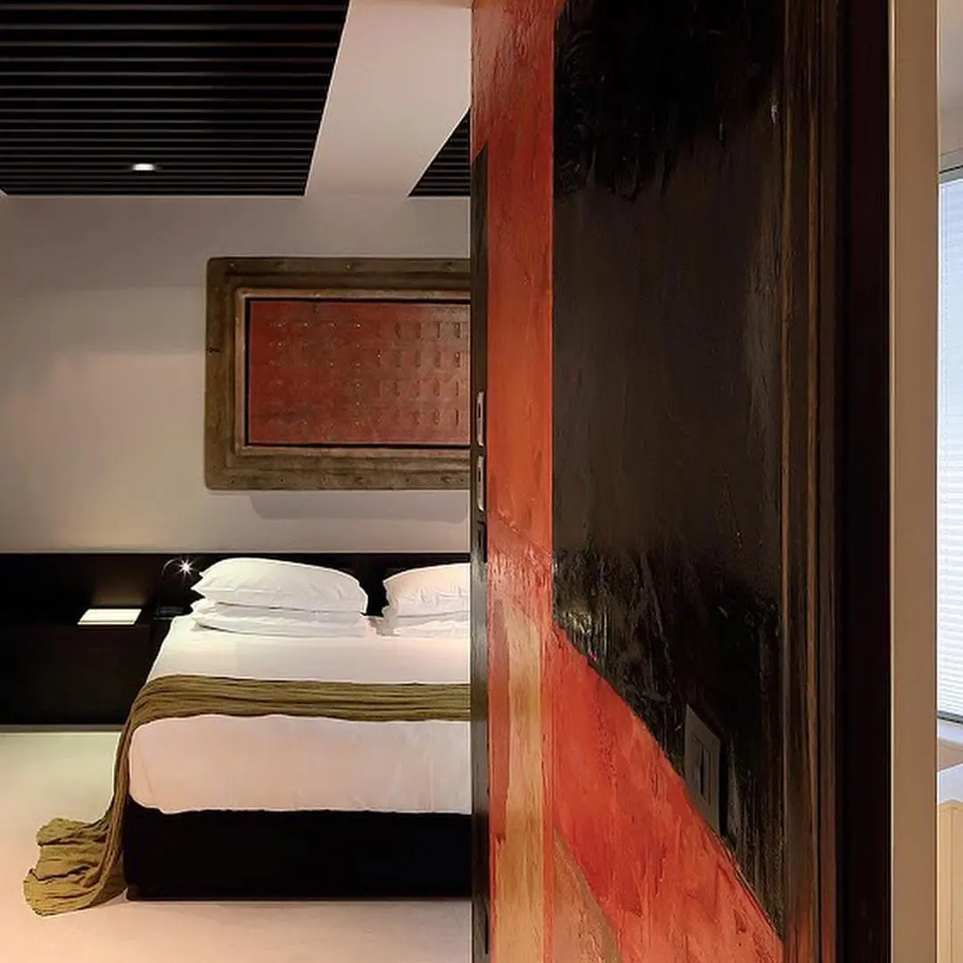 Bedroom with a weathered orange panel beside a sliding wood door