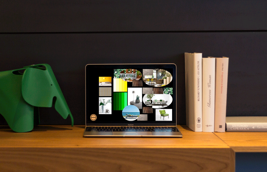 Laptop showing a photo mood board on a desk beside a green toy elephant and books