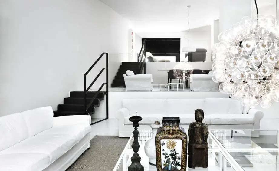 White living room with staircase, glass coffee table and bubble chandelier