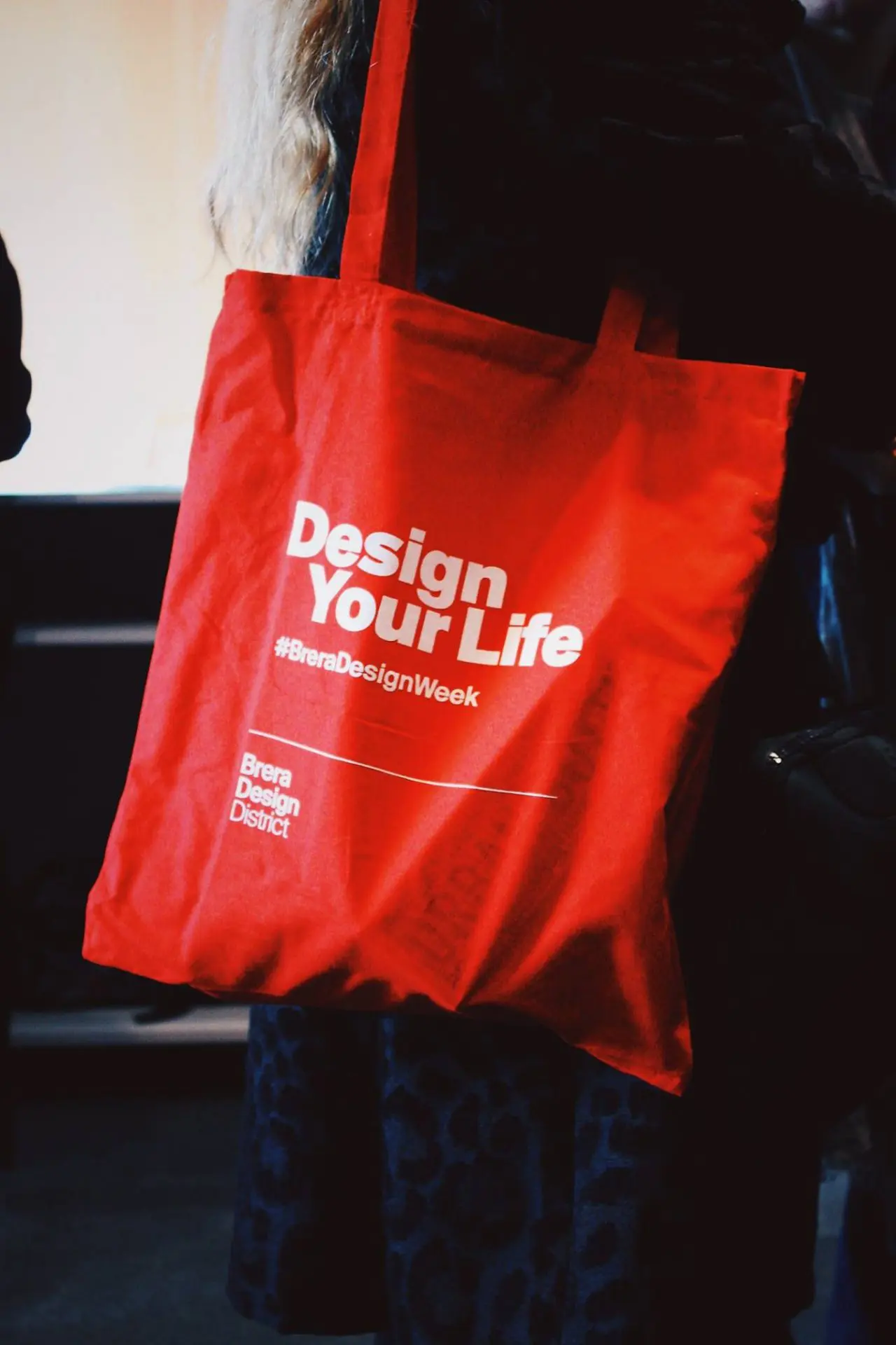 red tote bag with white text stating design your life
