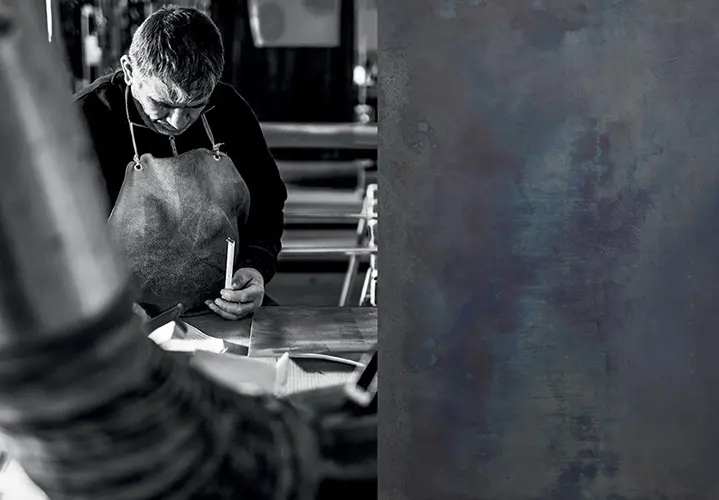 Black-and-white photo of a craftsman working leather at a workbench