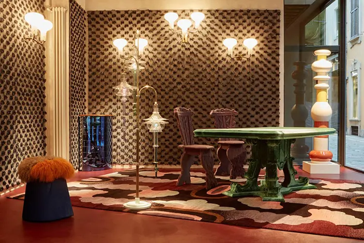 Eclectic showroom with patterned walls, ornate chairs and a green table on a red floor