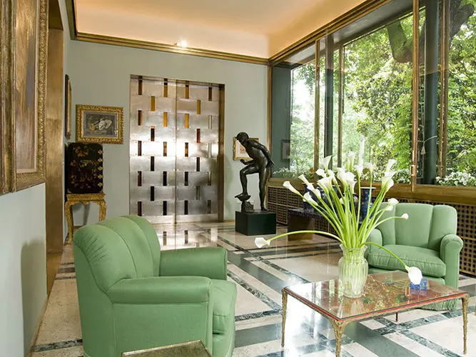Living room of Villa Necchi in Milan, with green armchairs and a marble floor