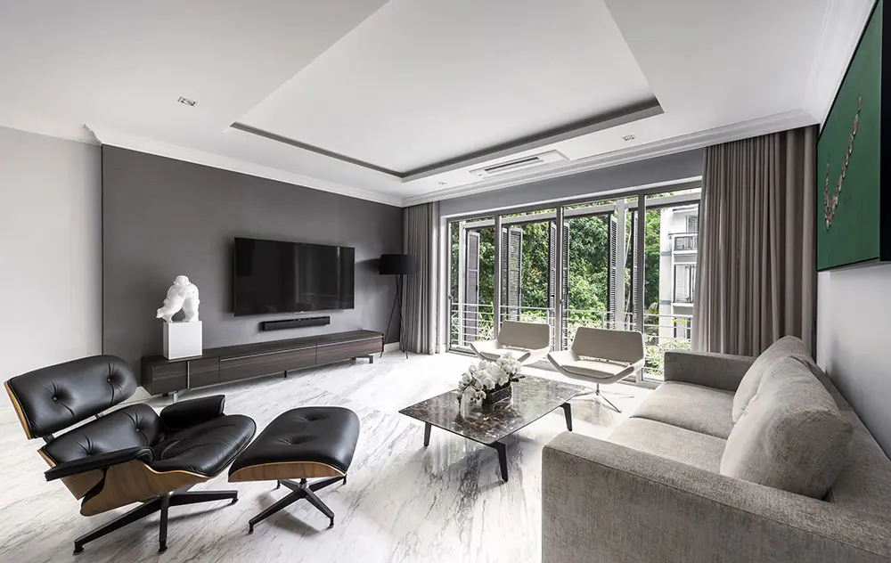 Living room with a black leather lounge chair, gray sofa and glass doors to greenery