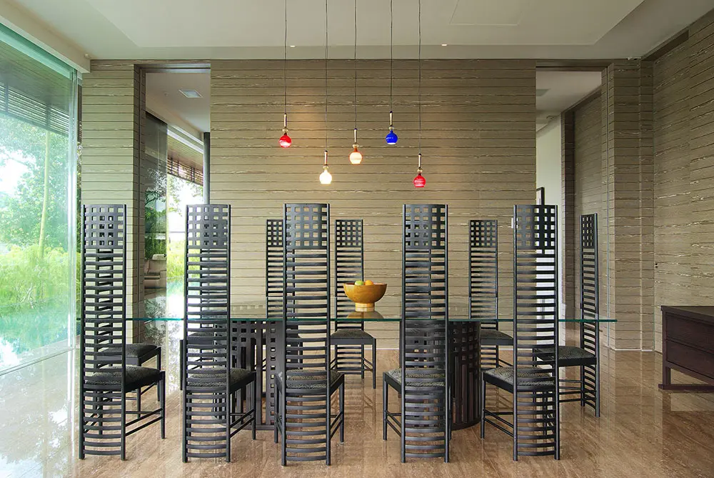 Dining room with tall slatted wood chairs, a glass table and colorful pendant lights