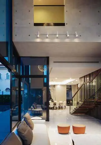 double-height entryway with glass doors, an orange side table and a staircase