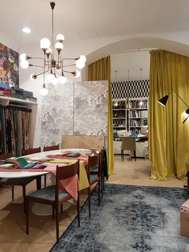 Textile showroom with a dining table set for fabric samples, mustard curtains and a chandelier