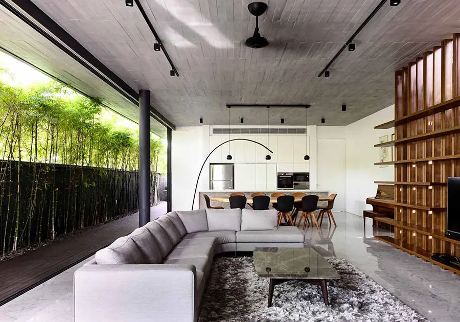 Living room open to a bamboo garden with a sectional sofa and dining area