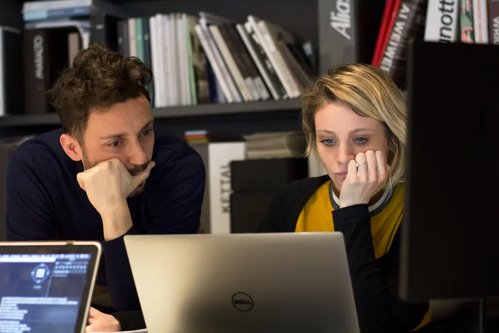 Two designers reviewing work together at a laptop in the studio